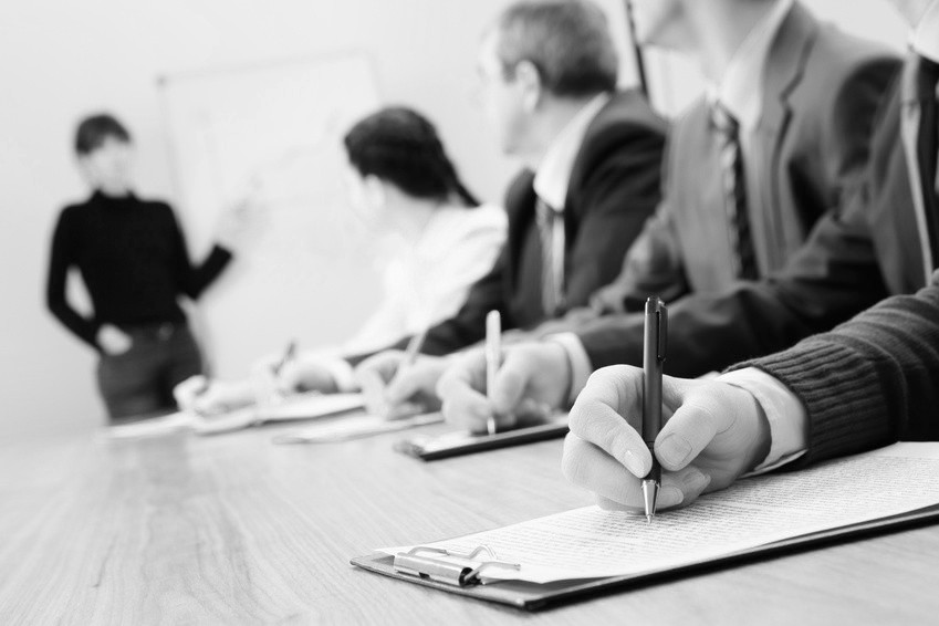 Row of business people making notes during presentation